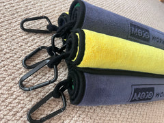 Rolled Mojo branded microfiber fishing rod covers in yellow and dark gray with black carabiners on textured surface