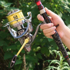 Hand holding a Mojo Surfmaster 12000 surfcasting reel and rod with green foliage background